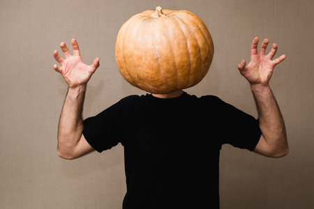 Young man in black t-shirt with a big pumpkin instead of his face. Boo gesture.の写真素材