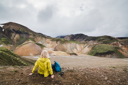 Woman in yellow raincoat overlooking the colorful mountains in Landmannalaugar national park, Icelandの写真素材