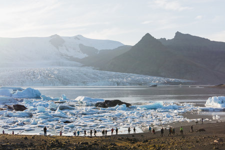 FJALLSARLON, ICELAND - AUGUST 2018: people walking on the shore of Vatnajokull glacier lagoon at sunset.のeditorial素材