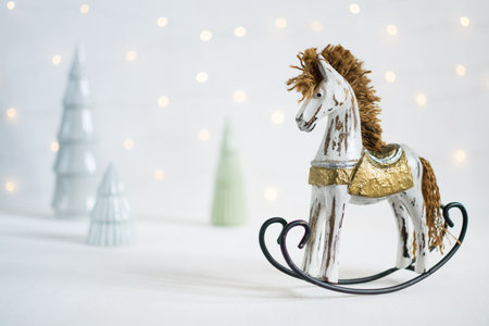 Rocking toy horse with Christmas trees and led garland lights on the backgroundの写真素材