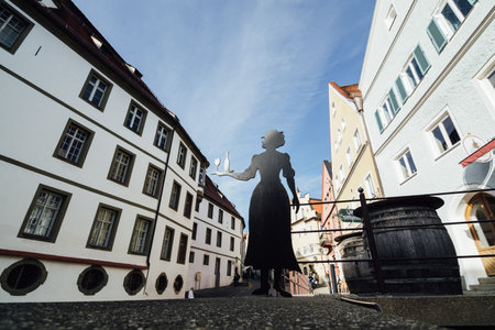 FUSSEN, GERMANY - DECEMBER 2018: the street of old town with waiter silhouette serving wine cut out of iron on the foreground.のeditorial素材