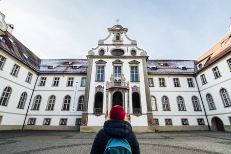 FUSSEN, GERMANY - DECEMBER 2018: woman in red hat standing at the backyard of Benedictine monastery...