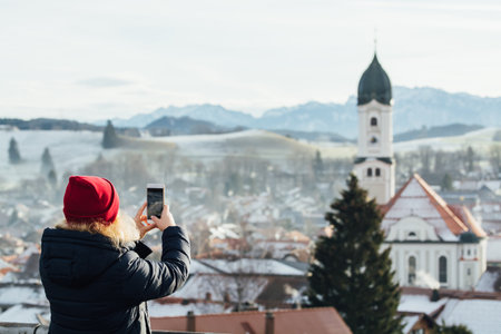 NESSELWANG, GERMANY - DECEMBER 2018: Woman taking a picture of Nesselwang old town in the morning.のeditorial素材