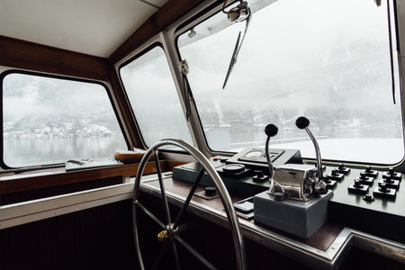 HALLSTATT, AUSTRIA - JANUARY 2019: view over Hallstatt town and Alps mountains from ferry boat captain's cabin. Steering wheel on the foreground.のeditorial素材