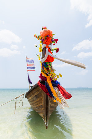 Traditional Thai long tail wooden boat with national flags and decoration moored at Railay beach in Krabi province, Thailand.のeditorial素材