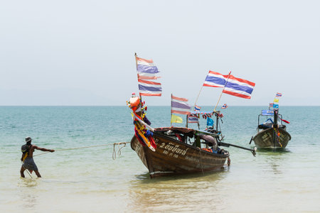 Krabi, Thailand - March 2019: long tail wooden boats with Thai flags moored at Railay beach.のeditorial素材