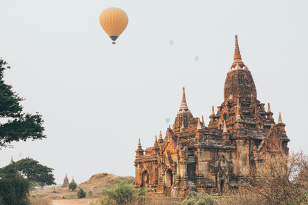 Hot air balloons flying over pagodas at Bagan temple complex at sunrise, Myanmar.