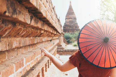 Woman with red umbrella overlooking pagoda and temple of ancient Bagan in Myanmarの写真素材
