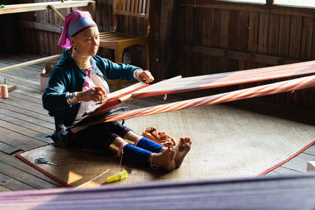 Inle, Myanmar - March 2019: Kayan Lahwi tribe long neck woman sits behind the loom in a tourist shop on Inle lakeのeditorial素材
