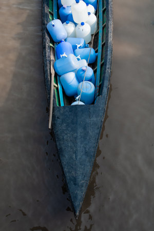 Wooden boat transporting bottles with fresh drinking water on Inle lake in Nyaung Shwe, Myanmar.