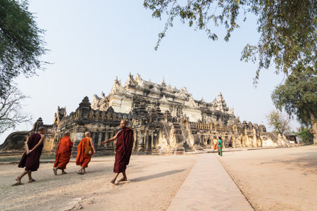 Inwa, Myanmar - April 2019: Buddhist monks walking next to Me Nu Brick Monastery in Mandalay region.