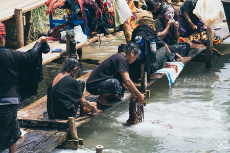 Indein, Myanmar - March 2019: Burmese women from PaO dragon people tribe washing clothes in the river close to Inle lake.のeditorial素材