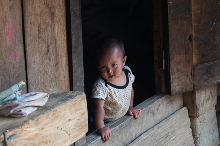 Sapa, Vietnam - May 2019: little Vietnamese child looking out over wooden house porchのeditorial素材