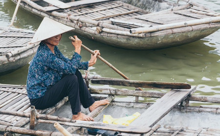 Ninh Binh, Vietnam - May 2019: Vietnamese woman in a wooden rowing boat going through Trang An nature park.のeditorial素材