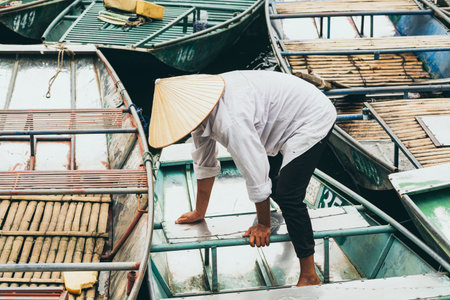 Ninh Binh, Vietnam - May 2019: Vietnamese woman in a wooden rowing boat going through Trang An nature park.のeditorial素材