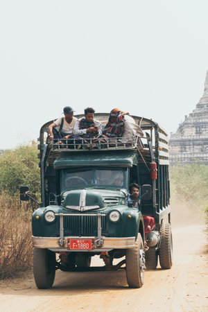 Bagan, Myanmar - March 2019: Burmese men riding retro truck next to Buddhist temple.のeditorial素材