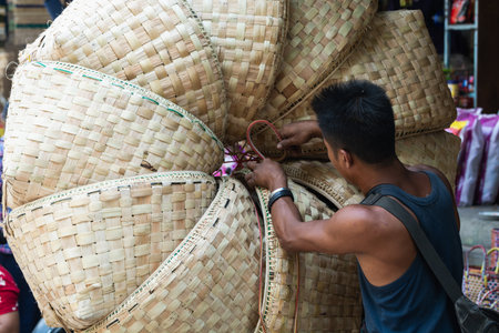 Mandalay, Myanmar - April 2019: Burmese man packing empty bamboo baskets on the street marketのeditorial素材