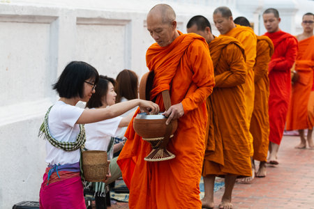 Luang Prabang, Laos - May 2019: Laotian people making offerings to Buddhist monks during traditional morning alms giving ceremonyのeditorial素材
