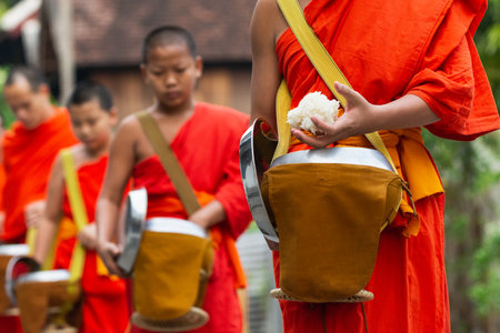 Luang Prabang, Laos - May 2019: Laotian Buddhist monks walking along the street during morning alms giving ceremonyのeditorial素材