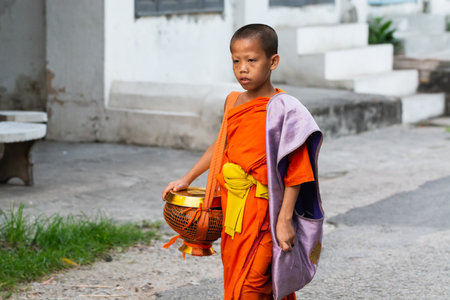 Luang Prabang, Laos - May 2019: Laotian Buddhist monk walking along the street during morning alms giving ceremonyのeditorial素材