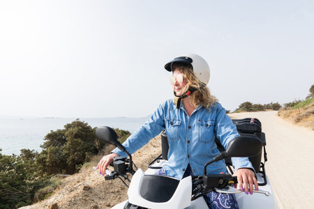 Young woman driving rental quad bike on seaside road in Naxos island, Greeceの写真素材