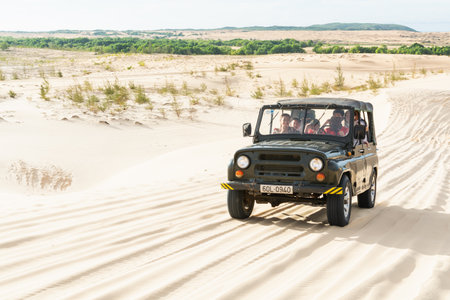 Mui Ne, Vietnam - June 2019: off-road vintage soviet car driving through desert sand dunes at sunrise.のeditorial素材