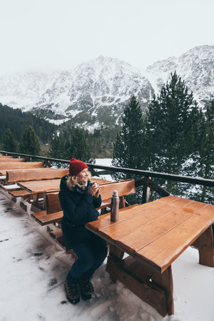 having a hot drink from   overlooking snowcapped High Tatra mountains peaks. Vertical orientationの写真素材