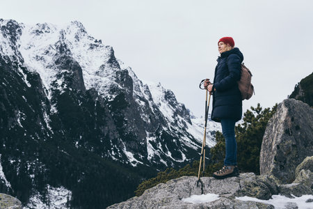 Woman trekking with walking poles in snowy High Tatra mountains in winter close to Popradske Pleso, Slovakia. Overlooking Studena dolina valleyの写真素材