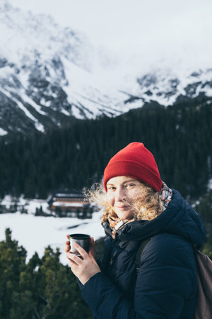 having a hot drink from   overlooking snowcapped High Tatra mountains peaks Looking into the cameraの写真素材