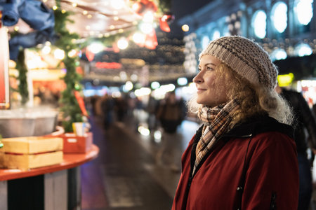 Smiling and happy blonde woman walking on the Christmas market in European cityの写真素材
