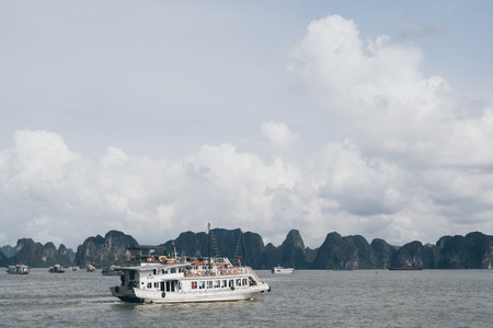 Tourist cruise ship sailing among limestone mountains in Halong Bay, Vietnam. Framing with tree leaves.の写真素材