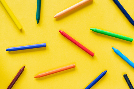 Yellow minimalistic background with colorful wax pastel crayon pencilsの写真素材