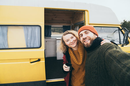 Young happy couple taking selfie in front of their yellow camper vanの写真素材