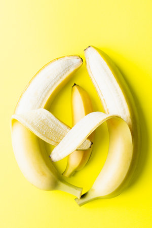 Conceptual image of two big banana parents holding a small baby banana, resembling parenthood and loveの写真素材