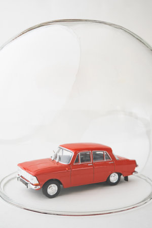 Red toy car inside a glass ball. Conceptual image of insurance coverage and safety protection. Vertical orientation.の写真素材