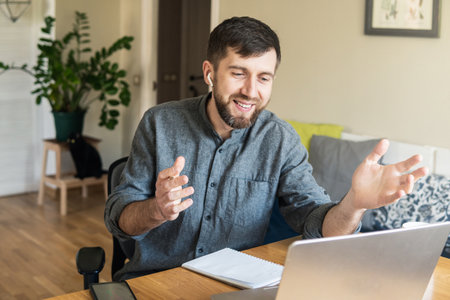 Handsome Eastern European man working from home during Corona virus quarantine lockdown, having online video chat with his colleaguesの写真素材