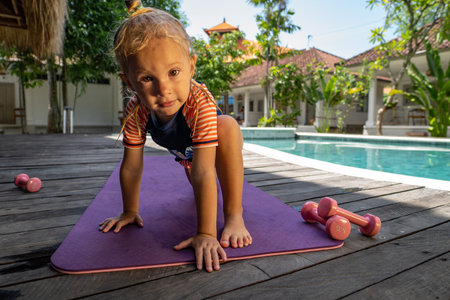 little girl in protective mask practicing yoga near swimming poolの写真素材