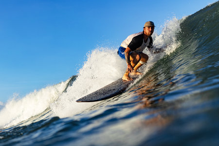 Handsome young adult surfer rides the waves of ocean at the surf spotの写真素材