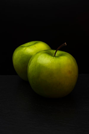 Two ripe fresh green apples on black backgroundの写真素材