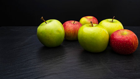 Three ripe fresh green apples and tree red apples on black backgroundの写真素材