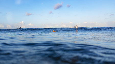 Three surfer swims on surfboards of the ocean at the surf spotの写真素材