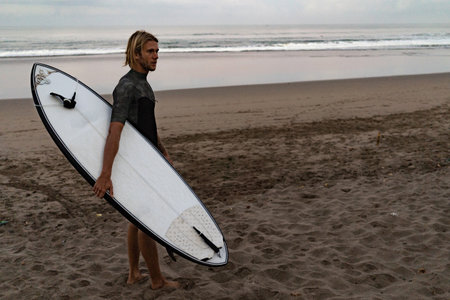 A surfer walking in from the water after a day out on the wavesの写真素材