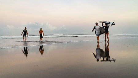 Three surfers man and beautiful girl with surfboards look at sunriseの写真素材