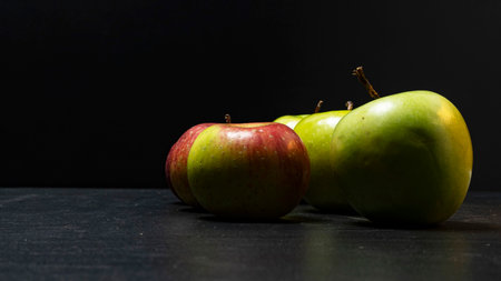 Three ripe fresh green apples and two red apples on black backgroundの写真素材