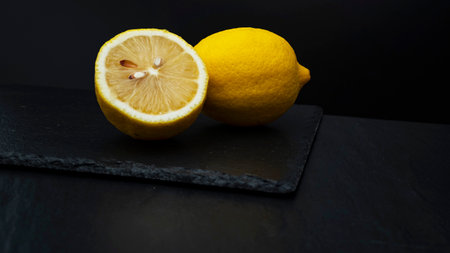 Close-up of a juicy ripe lemons on a serving board on dark background.の写真素材