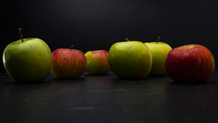 Three ripe fresh green apples and tree red apples on black backgroundの写真素材