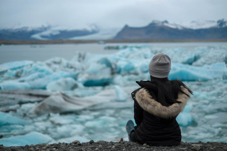 women traveller sit on the ground and looking for iceberg in jokulsarlon glacier lagoonの写真素材