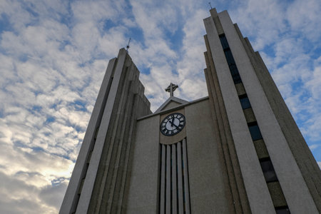 big church Akureyrarkirkja in Akureyri city of northern iceland with cloudy sky  and clock time 1.25 PMの写真素材