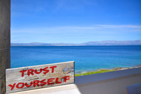 Trust yourself on old plank with blurred sea backgroundの写真素材