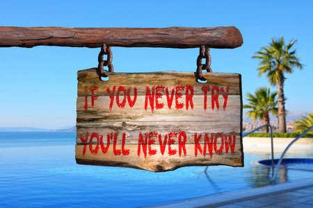 If you newer try, you\'ll never know motivational phrase sign on old wood with blurred backgroundの写真素材